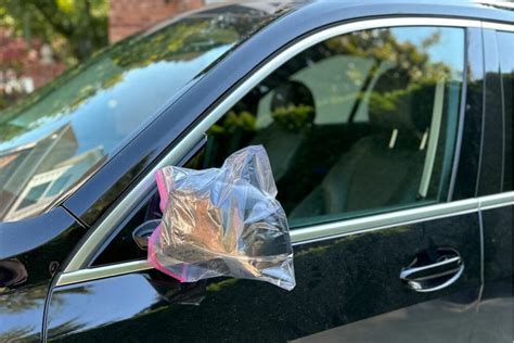 putting plastic bags on car mirror.